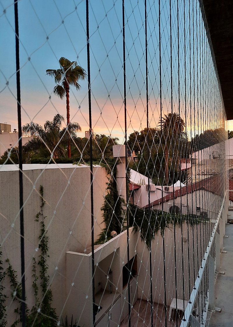 Red de seguridad en balcón con vista abierta al atardecer