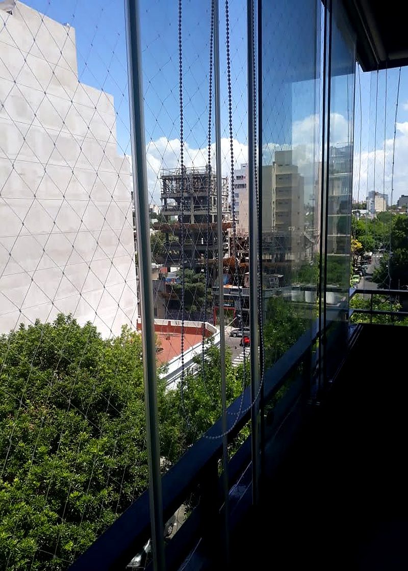 Red de seguridad en balcón vidriado con vista a los árboles